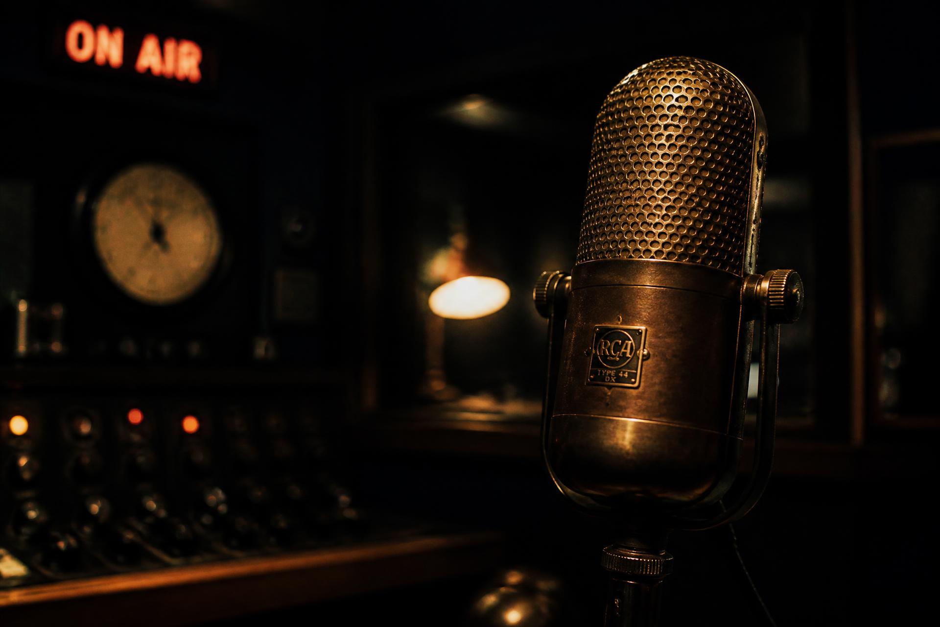 Vintage broadcast microphone in a dark studio with an ON AIR sign
